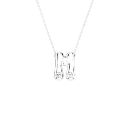 A silver initial necklace featuring the letter 'M' with two small clear gemstones set into the lower portions of the letter, suspended from a delicate silver chain against a solid white background.
