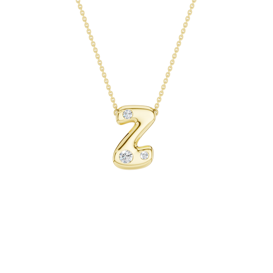 A product shot of a yellow gold necklace on a dark transparent background. The fine cable chain is attached to either side of a smooth, bubble-font letter 'Z' pendant. The gold 'Z' is embellished with three sparkling, flush-set round diamonds: one on the top curve and two varying in size along the bottom curve.