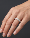 Close-up of a hand resting against a dark gray background, wearing a thick white metal band featuring a row of large, round-cut diamonds.