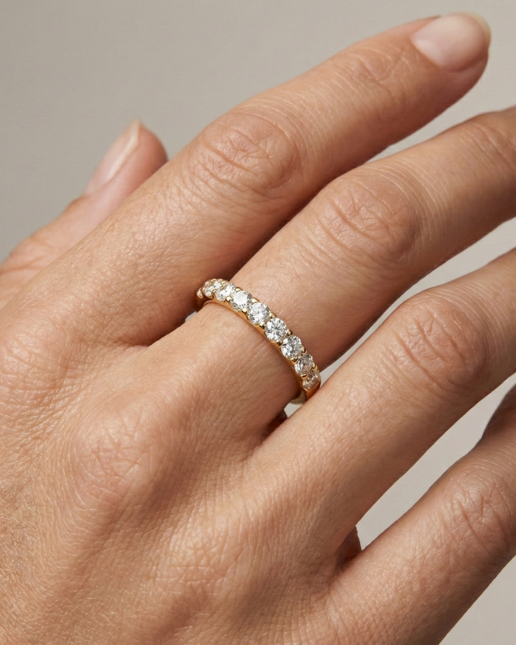 A dainty 14k yellow gold wedding band featuring 0.50 total carats of round-cut lab-grown diamonds in a classic half eternity setting on hand.