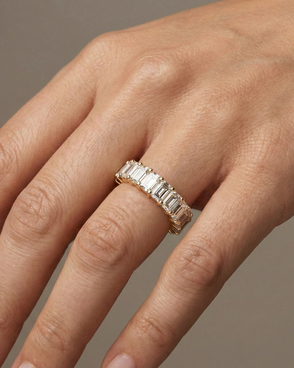 A breathtaking 14k yellow gold 2/3 eternity wedding band featuring 3.0 total carats of shimmering emerald-cut lab-grown diamonds on hand.