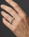 A top-down view of a 14K yellow gold eternity ring with a continuous line of bold, horizontally-set emerald-cut diamonds on a hand.