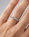 A top-down view of a 14K white gold braided ring with a continuous pavé diamond design on hand.