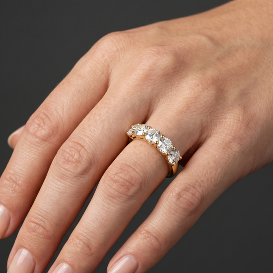 Lifestyle view of a model wearing a luxurious 14k yellow gold five-stone diamond ring featuring a row of large, uniform round brilliant-cut diamonds.