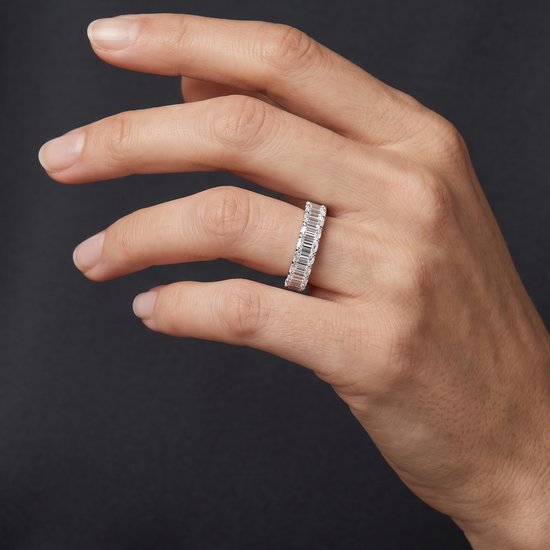 Lifestyle view of a model wearing a heavy-carat 14k yellow gold eternity ring featuring exceptionally large, vertically set emerald-cut diamonds.