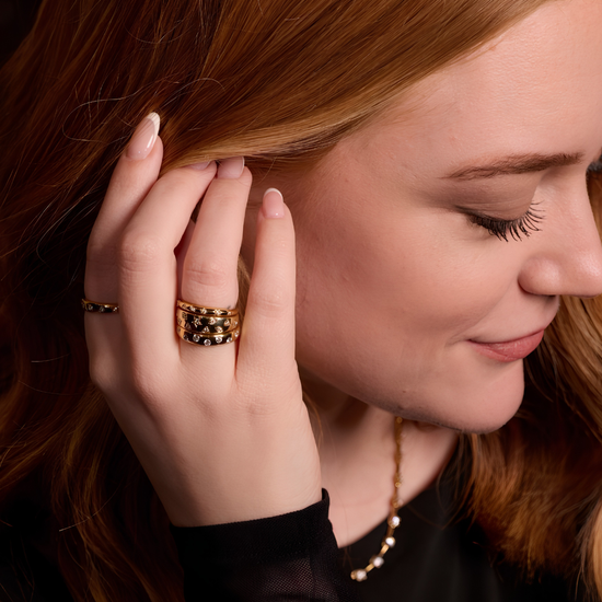 A high-polish, slender 14K yellow gold stackable ring by Amorati, delicately detailed with petite star-shaped insets, each set with a shimmering round lab-grown diamond, elegantly displayed on a model’s hand. Amorati’s signature F O U R T E E N T H Collection.
