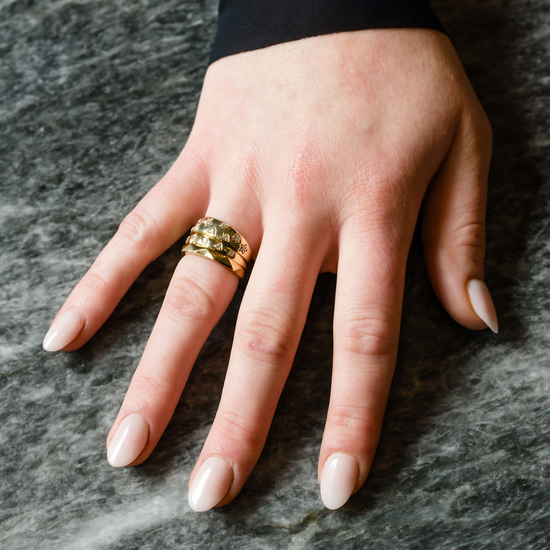 A lifestyle view of the Fourteenth Collection rose gold star studded diamond ring, highlighting sculpted star-shaped bezel settings and round diamonds embedded into a substantial, polished band.