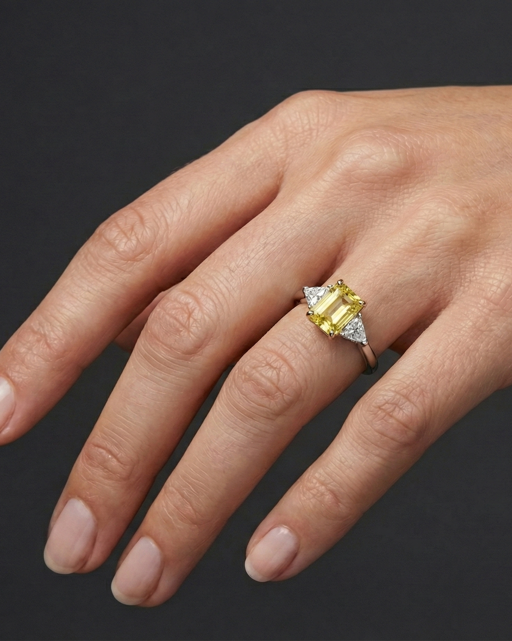 2.91 cttw Soleil Radiant-Cut Three-Stone Diamond Ring on hand. Featuring a 2.50ct IGI Certified Vivid Canary center and Trillion-Cut E-F/VS+ side stones in Solid 14K Gold with Insured Free Shipping.