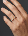 Close-up of a hand wearing a delicate yellow gold diamond ring, featuring pear-cut diamonds set on a slim pavé band, photographed against a dark background to highlight refined sparkle and elegant everyday styling.