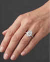 Elegant white gold engagement ring featuring a large oval-cut center diamond and a pavé diamond band, worn on a woman's hand.