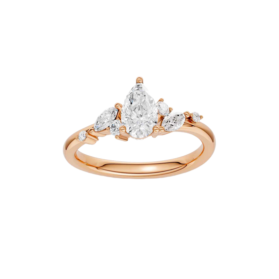 A top-down view of a 14K rose gold ring with a three-stone cluster of round and pear-shaped gems.