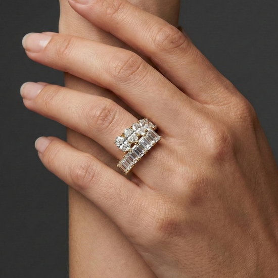Close-up of a hand wearing a stacked white gold diamond ring design, featuring multiple rows of round and baguette-cut diamonds, photographed against a dark background to highlight layered sparkle and modern luxury styling.