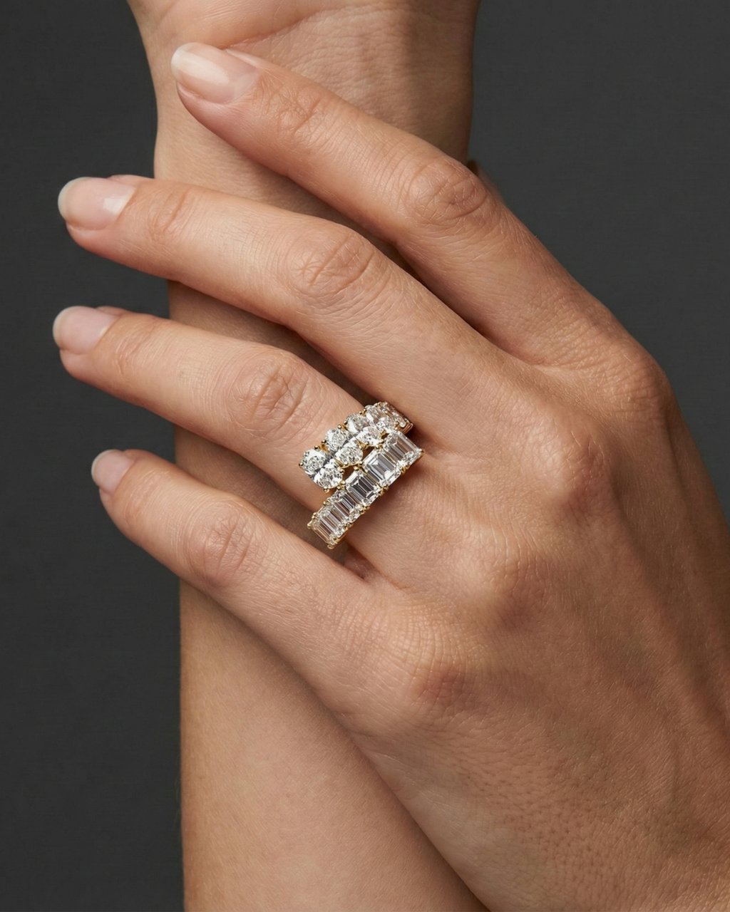 Close-up of a hand wearing a stacked white gold diamond ring design, featuring multiple rows of round and baguette-cut diamonds, photographed against a dark background to highlight layered sparkle and modern luxury styling.