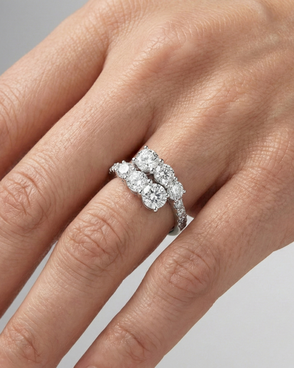 Yellow gold diamond ring resting on black marble, featuring multiple round brilliant-cut diamonds arranged in a modern layered design with pavé diamonds on hand.