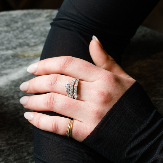 An on finger view of a 14K white gold open-shank ring with a continuous spiral design and a pavé diamond surface