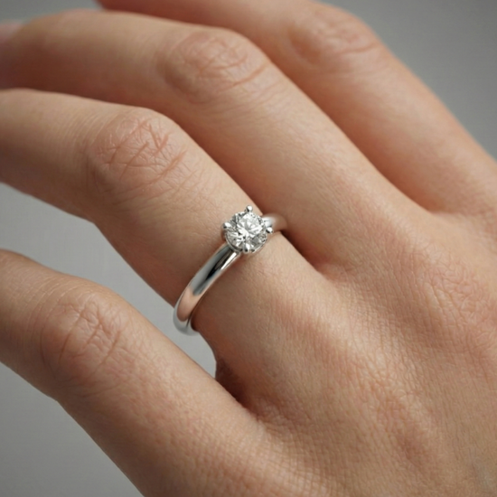 A top-down view of a 14K yellow gold ring with a round diamond and a pavé halo on hand.