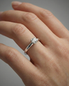 A top-down view of a 14K yellow gold ring with a round diamond and a pavé halo on hand.
