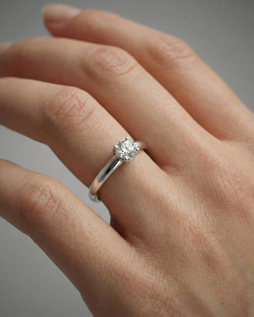 A top-down view of a 14K yellow gold ring with a round diamond and a pavé halo on hand.