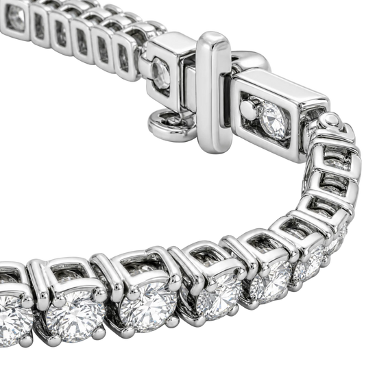 A close-up of a silver tennis bracelet with round-cut clear stones in a box setting and a polished clasp, photographed on a white background.
