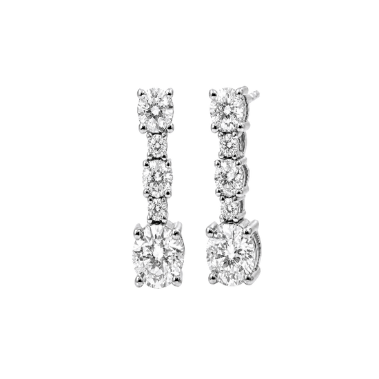 A pair of silver-toned drop earrings with a vertical channel setting of round and oval-cut clear stones, including a larger oval stone at the bottom, shown on a plain white background.