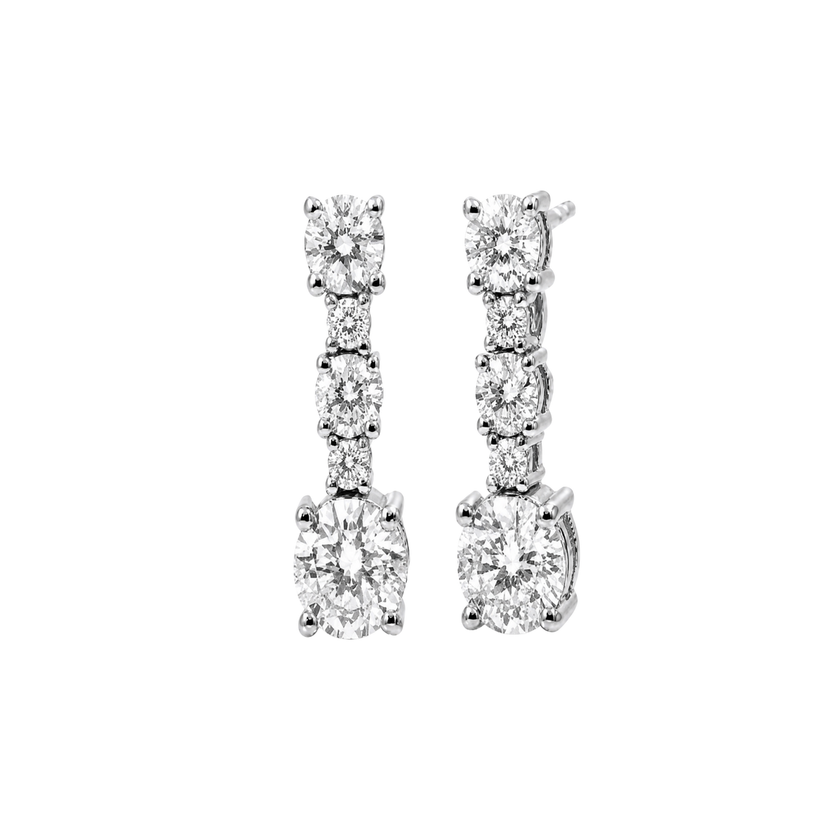A pair of silver-toned drop earrings with a vertical channel setting of round and oval-cut clear stones, including a larger oval stone at the bottom, shown on a plain white background.