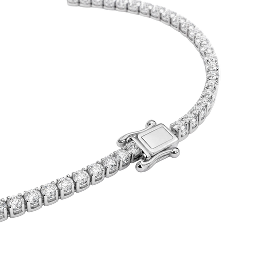 A close-up studio shot of a tennis-style necklace with a silver-toned clasp and clear stones, photographed on a clean white background.