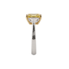 A straight-on side view of an engagement ring resting vertically against a black background, showcasing the height and profile of the setting. At the top, the edge of a pastel yellow center diamond is visible within a yellow gold setting. The smooth white metal band sweeps upward to support the setting, partially revealing the side profile of a clear accent diamond.