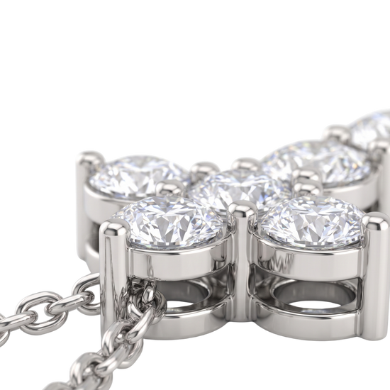 Extreme close-up of the base of a white gold diamond cross pendant, showcasing the intricate metal basket setting beneath the sparkling stones and the attached chain.