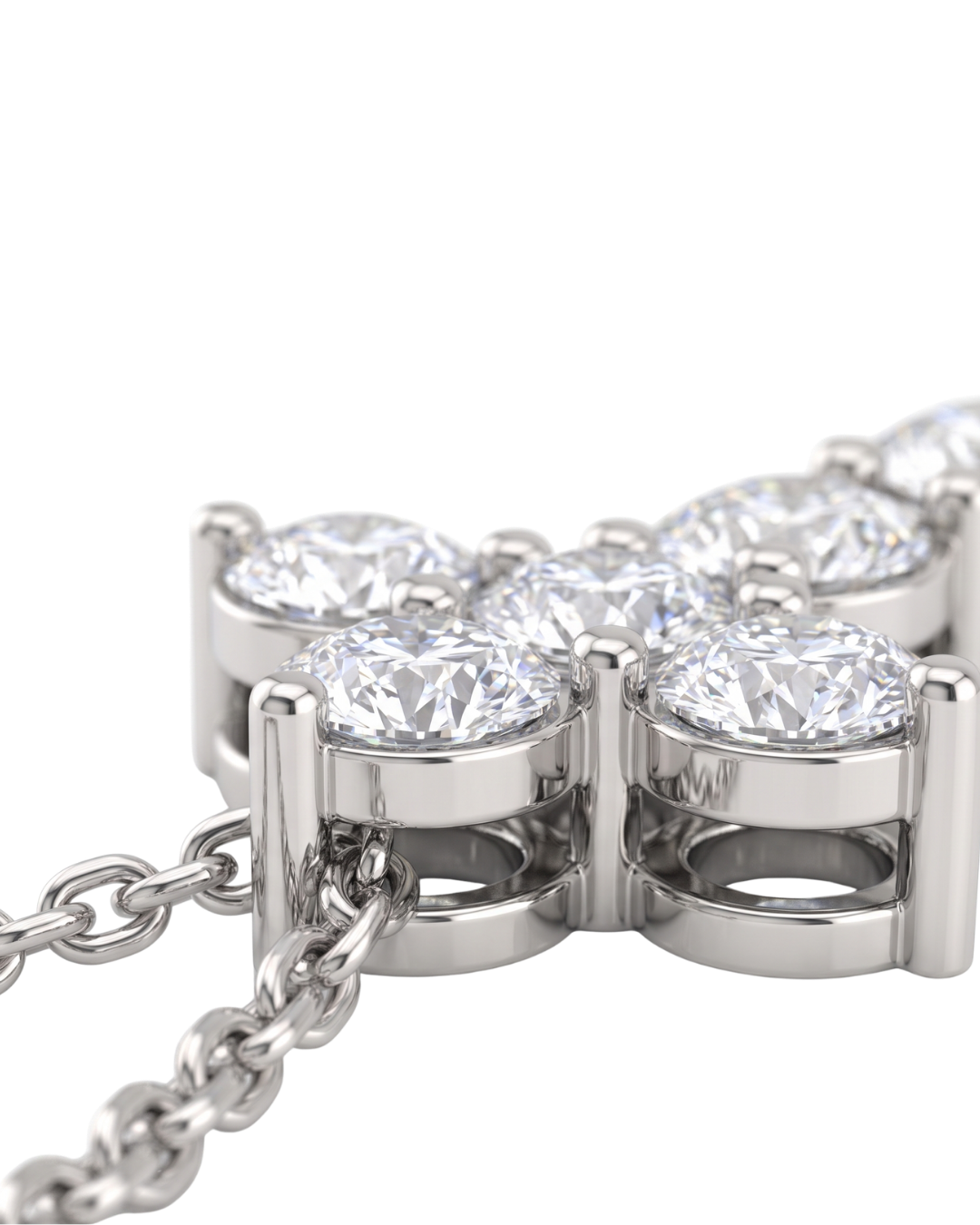 Extreme close-up of the base of a white gold diamond cross pendant, showcasing the intricate metal basket setting beneath the sparkling stones and the attached chain.